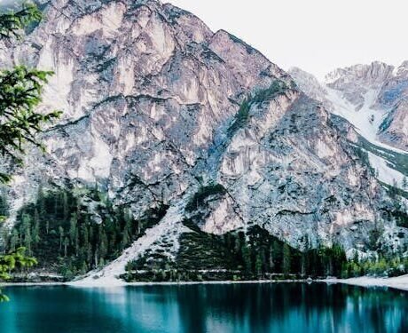 Serene mountain lake with stunning reflections in Braies, Italy, surrounded by trees.