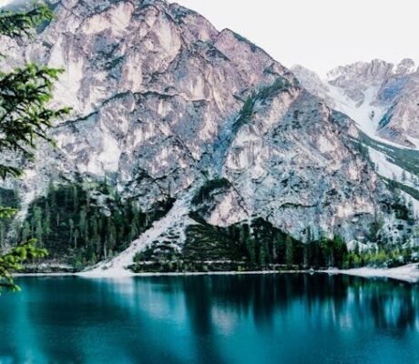 Serene mountain lake with stunning reflections in Braies, Italy, surrounded by trees.